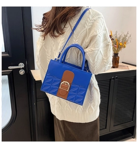 Détail d'un sac à main bleu vif avec des accents marron porté à l'épaule par un mannequin