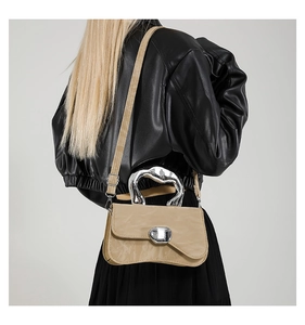 Detail of beige crossbody bag with silver liquid metal handle and marble texture