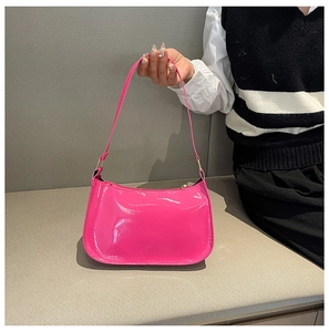 Detail of pink patent leather shoulder bag with glossy mirror finish and gold hardware