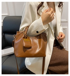 Close-up of brown vintage leather bucket bag with hanging mini pouch and shoulder strap