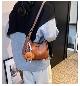 Detail of vintage brown leather crescent bag with teddy bear charm and fashion label