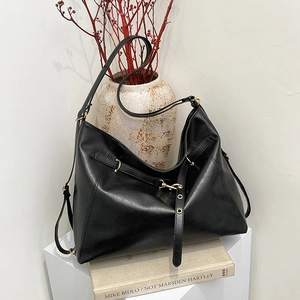 Retro black large tote bag with gold buckles on a minimalist display stand