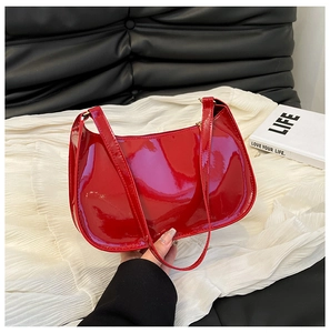 Detail of red glossy patent leather hobo bag with sleek zipper and retro shoulder strap