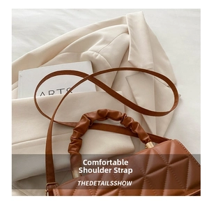 Detail show of brown quilted crossbody bag with pleated handle and metal chain accents