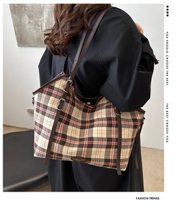 Detail of checkered canvas tote bag with adjustable brown leather shoulder strap and buckle