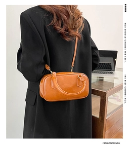Brown vintage leather bowling bag with gold hardware worn as a crossbody office bag