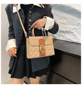 Detailansicht der beigefarbenen Stepptasche mit braunen Riemen und goldener Schnalle