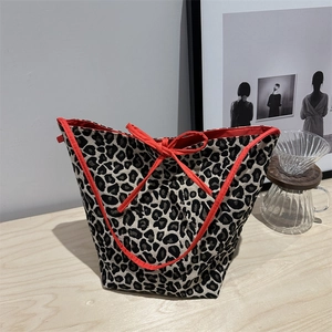 Chic leopard print tote bag with red bow accent and contrast ribbon on a wooden table