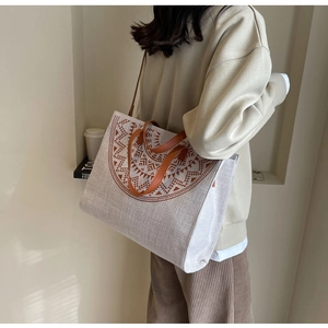 Detail view of large ethnic pattern tote bag with leather straps on model's shoulder
