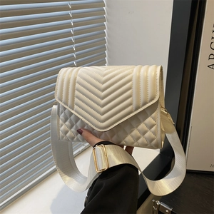 White quilted shoulder bag with wide strap and V-shaped stitching in soft natural light