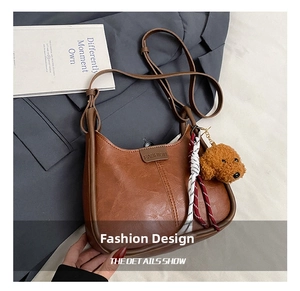 Detailed shot of brown PU leather shoulder bag with plush bear charm and strap