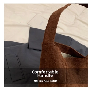 Detail of wide handles and soft brown suede texture on a large minimalist tote bag