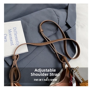 Detail view of the adjustable brown leather shoulder strap and metallic chain accessory