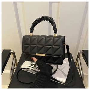 Detail of quilted black leather crossbody bag with pleated handle and gold hardware