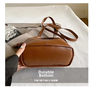 Detail view of the durable flat rectangular base on a brown leather bucket bag