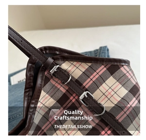 Detail of plaid canvas tote with brown leather strap and silver metal buckle hardware