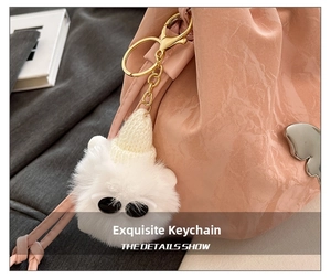 Close-up of white plush doll charm with sunglasses and knit hat on a pink bucket bag
