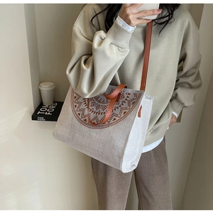 Detail of canvas tote bag with brown geometric pattern and leather straps on model