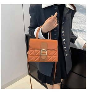 Detailansicht der караmelbraunen Lederhandtasche mit Steppmuster und goldener D-Schnalle