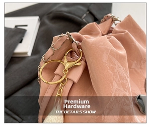 Close-up of pink glossy leather bucket bag with gold chain strap and metal hardware