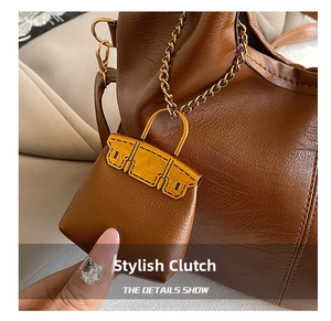 Close-up of a mini brown leather handbag charm with gold metal clasp and chain