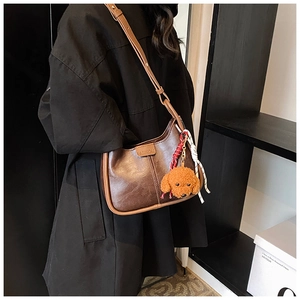 Detail of dark brown leather hobo bag with teddy charm and adjustable shoulder strap