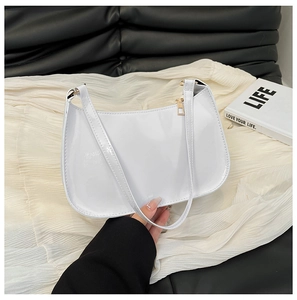 Detail of white glossy patent leather underarm bag with gold zipper and sleek strap