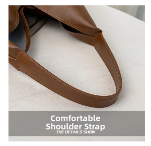 Close-up of wide soft leather shoulder strap with neat stitching on vintage brown tote bag