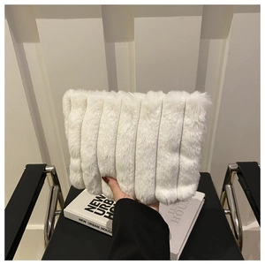 Détail d'un sac à main en fausse fourrure blanche avec texture à rayures verticales et livre