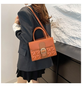 Braun-orangefarbene Ledertasche mit geometrischer Textur und goldener Schnalle am Modell