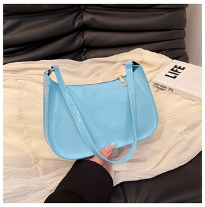 Close-up of light blue patent leather shoulder bag with gold zipper and sleek texture