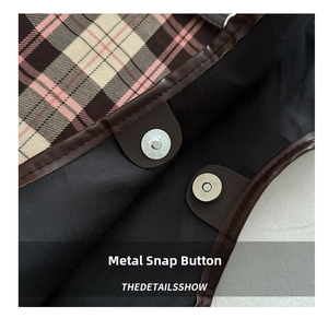 Detail view of the magnetic metal snap closure on a checkered canvas tote bag