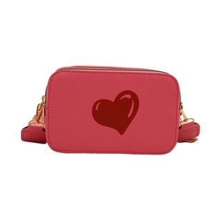 Pink crossbody camera bag with red heart print and golden zipper in pebble leather