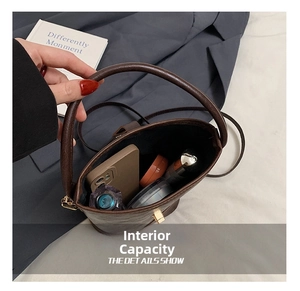 Detail showing the internal storage capacity for phone and cosmetics in the brown bucket bag
