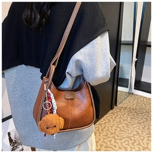 Detail of minimalist brown PU leather shoulder bag with plush charm and fashion tag