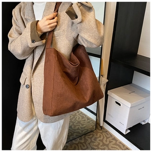 Detail shot of a large brown matte faux suede tote bag worn over a beige blazer