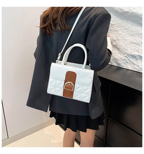 Détail d'un sac bandoulière matelassé chic avec patch cuir marron et boucle dorée
