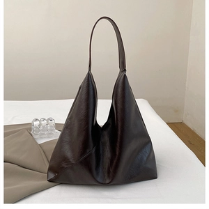 Detail of dark brown large tote bag with wide strap on white bedding in minimalist style