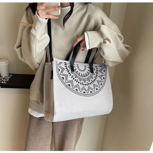 Detail of canvas tote bag featuring black geometric print and detachable shoulder strap