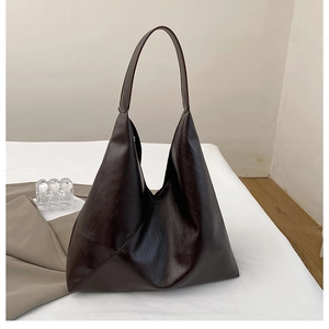 Detail of a large brown tote bag with asymmetric stitching on soft PU leather fabric
