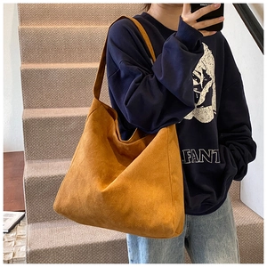 Detail of a large ginger faux suede hobo bag showing soft matte texture and wide shoulder strap