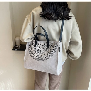 Detail of the woven tote bag showing the black tribal pattern and leather straps