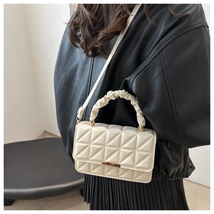 Detail of quilted crossbody bag with gold metal buckle and pleated cloud handle