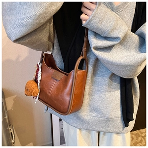 Detail of caramel faux leather shoulder bag featuring FASHION label and plush bear charm