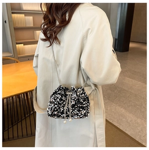 Detail of sequin bucket bag featuring pearl drawstring and metal chain strap