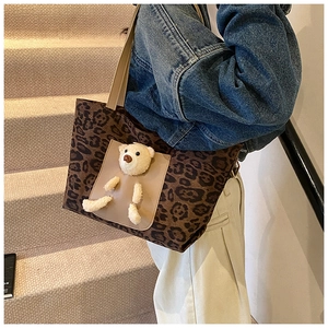 Detail of leopard print tote bag with a 3D plush bear tucked into a leather front pocket