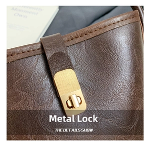 Detailed shot of golden twist lock hardware on vintage brown textured bucket bag