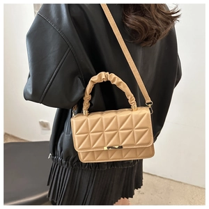 Chic beige quilted small square bag with pleated handle and gold buckle on a model
