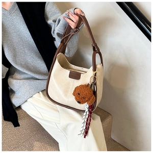Detailed view of beige shoulder bag with brown trim and cute plush puppy charm