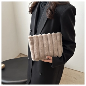 Detail der hellbraunen Kunstfell-Clutch mit vertikaler Rippenstruktur und weichem Plüschmaterial